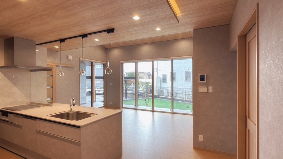 大きな窓からデッキと庭が見える明るいリビング