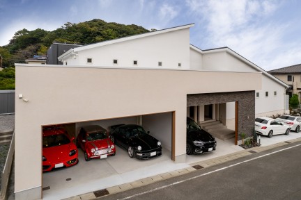 広々としたビルトインガレージに複数の車が整然と並ぶ邸宅の外観。シャッター付きでセキュリティも高く、車好きにはたまらない空間。趣味の道具やアウトドア用品なども収納可能。