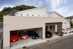 広々としたビルトインガレージに複数の車が整然と並ぶ邸宅の外観。シャッター付きでセキュリティも高く、車好きにはたまらない空間。趣味の道具やアウトドア用品なども収納可能。