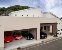 広々としたビルトインガレージに複数の車が整然と並ぶ邸宅の外観。シャッター付きでセキュリティも高く、車好きにはたまらない空間。趣味の道具やアウトドア用品なども収納可能。
